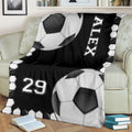 Black and white soccer throw blanket draped over an armchair with bold ball artwork