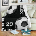 Soccer blanket displayed on a couch with black and white ball graphics and border design