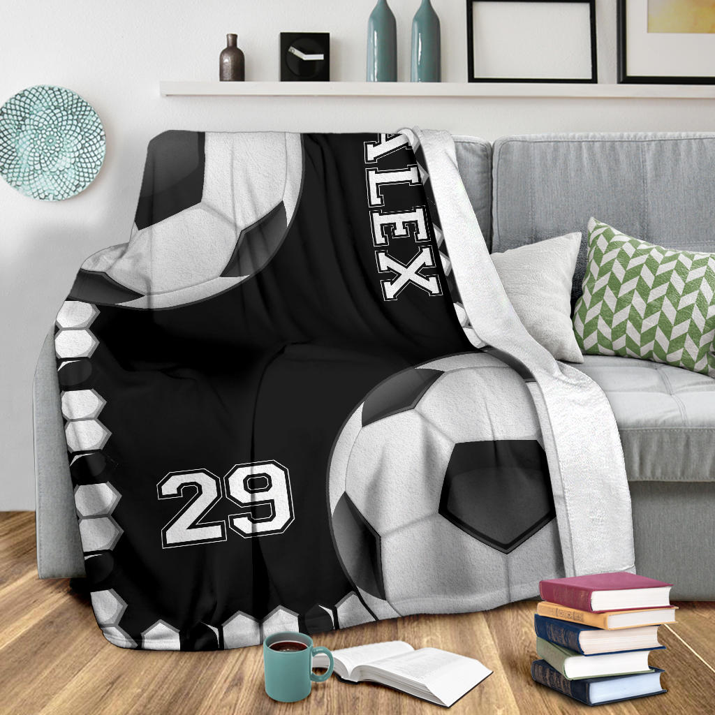 Black soccer throw blanket styled on a modern sofa with bold monochrome sports artwork
