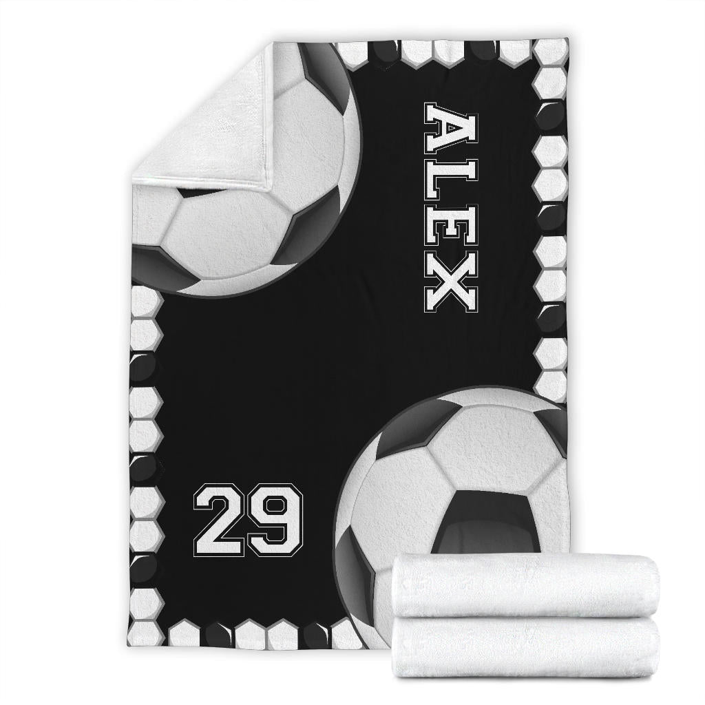 Soccer blanket product display featuring black and white ball artwork and folded blanket detail