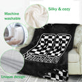 Racing blanket draped over a couch with checkered flag artwork and a close-up of its soft texture
