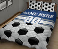 Blue and white soccer quilt blanket spread across a bed with bold black and white ball graphics