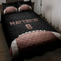 Black football quilt blanket styled on a bed with football artwork and bold athletic bedroom decor