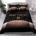 Football quilt bedding styled in a bright bedroom with bold black and brown sports artwork