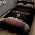 Close bedroom view of black football quilt blanket with football artwork and coordinating pillows