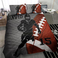 American football quilt blanket displayed on a bed with a helmeted player, football graphics, and gray and orange artwork