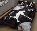 Baseball quilt bedding in a bedroom with a large batter silhouette, baseballs, and decorative red stitching