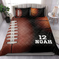 American football quilt bedding styled in a bedroom with bold brown, orange, black, and white graphics