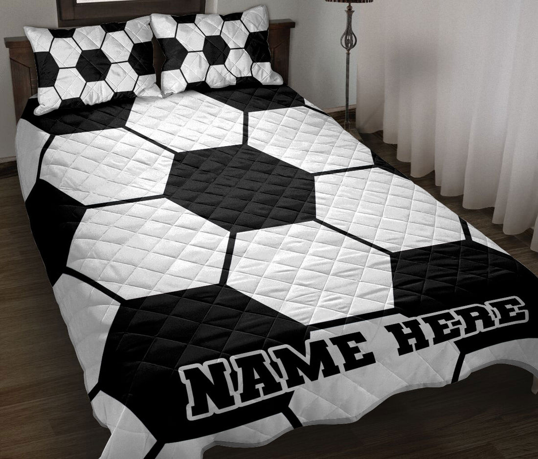 Black and white soccer ball quilt blanket styled on a bed with matching patterned pillows