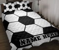 Black and white soccer ball quilt blanket styled on a bed with matching patterned pillows