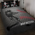Baseball quilt blanket displayed on a bed with black and gray artwork, red baseball stitching, and batting silhouettes