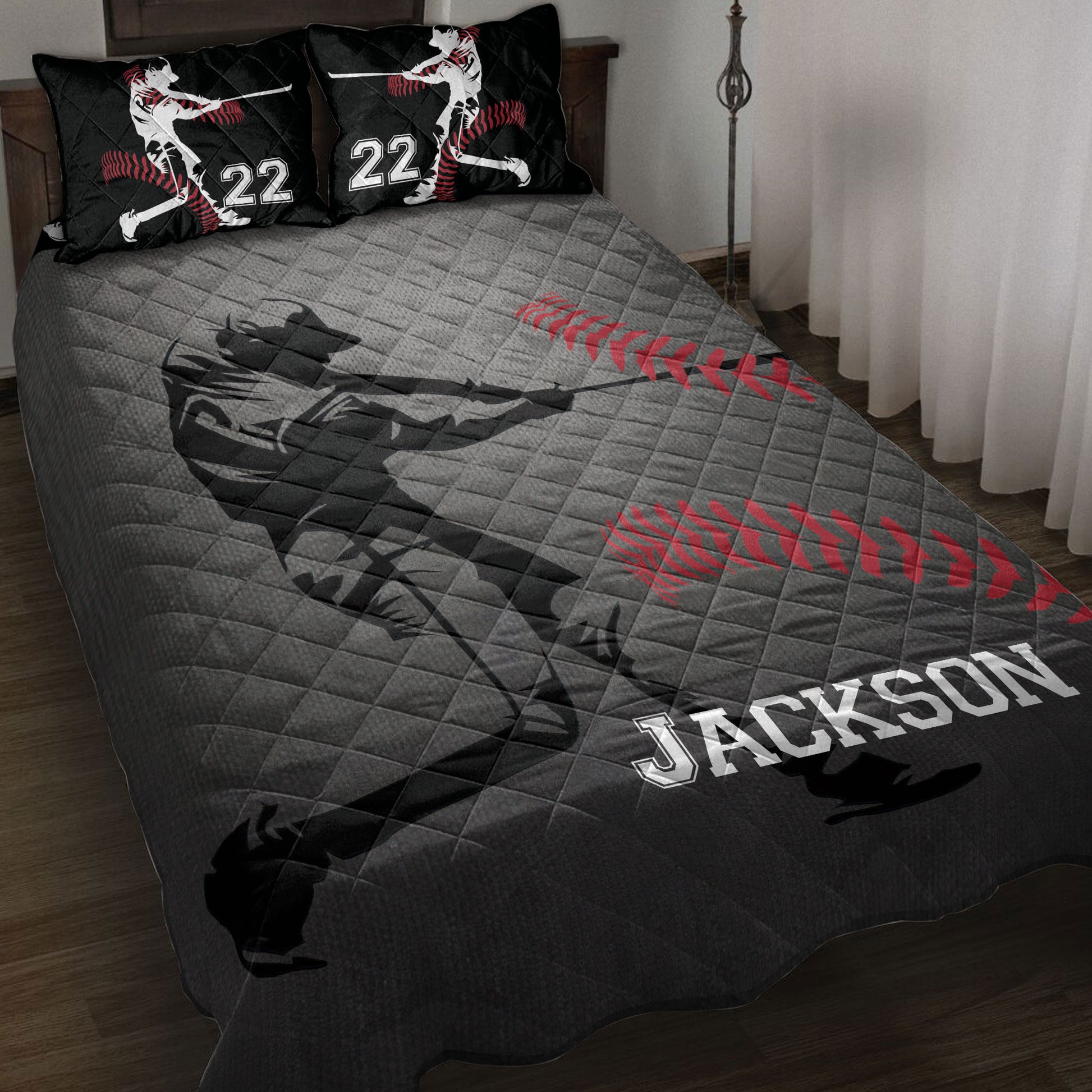 Baseball quilt blanket displayed on a bed with black and gray artwork, red baseball stitching, and batting silhouettes