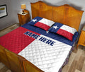 Texas flag quilt blanket styled across a bedroom with a large white Lone Star and patriotic red, white, and blue design