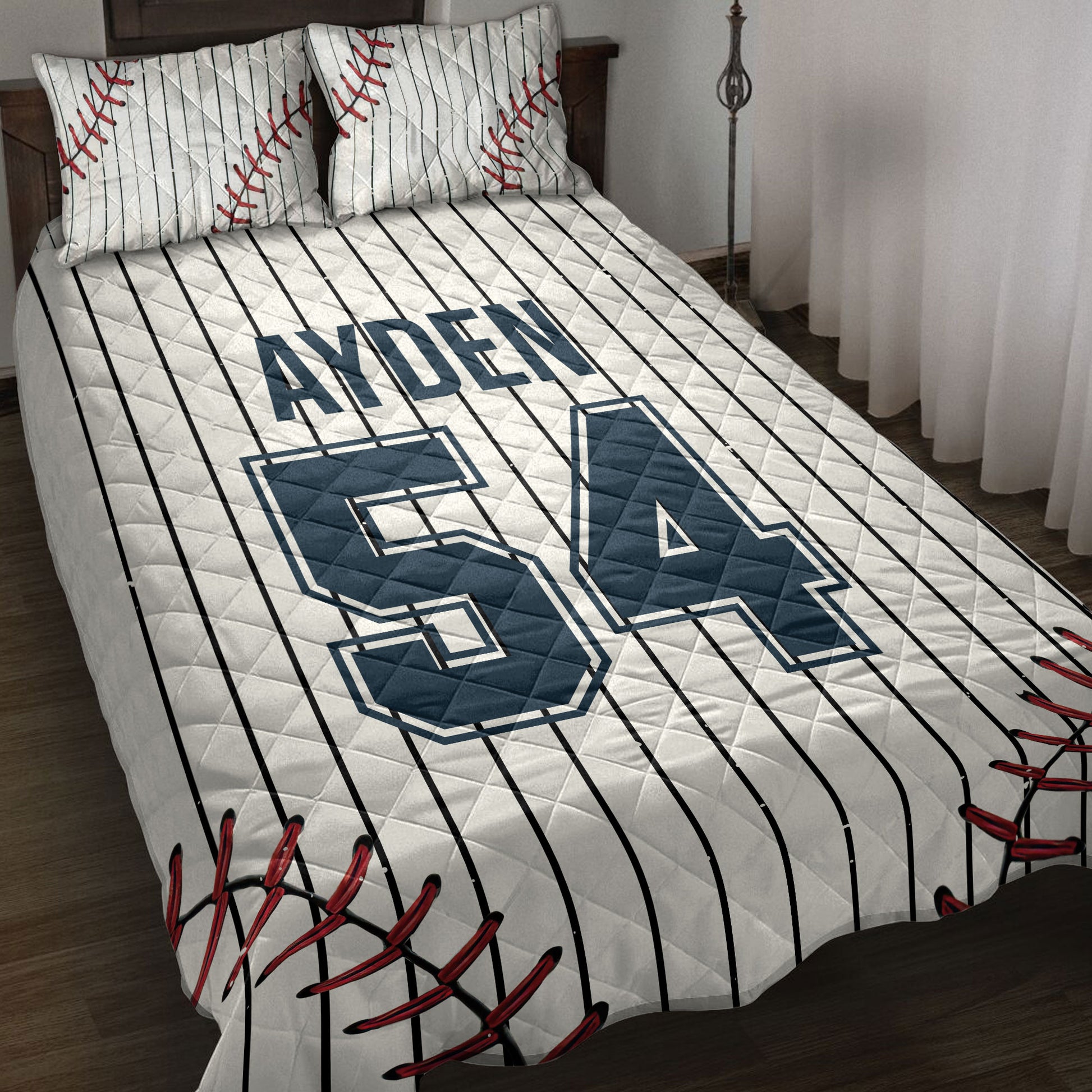 Baseball quilt blanket styled on a bed with pinstripes, red baseball stitching, and navy sports artwork