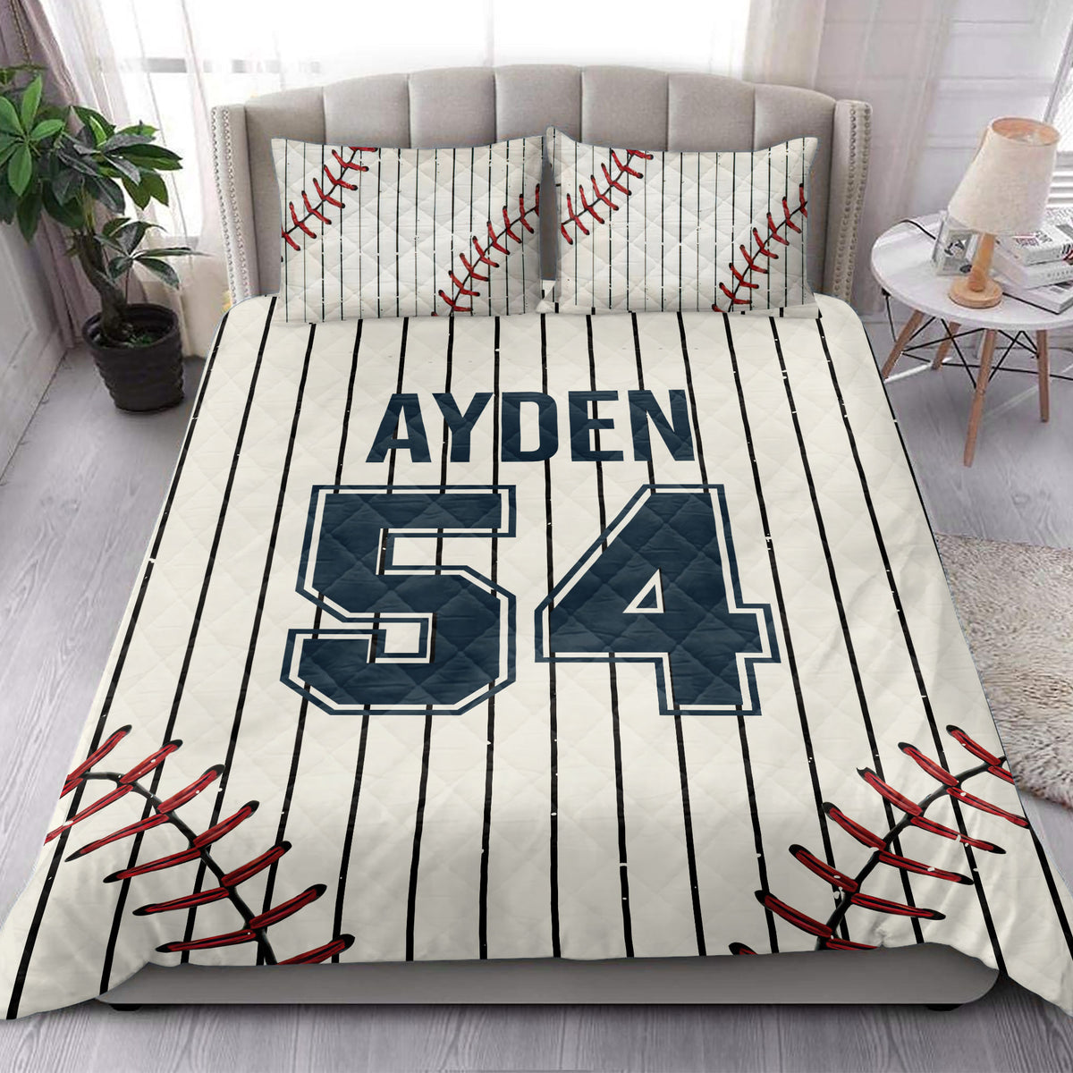Baseball quilt blanket styled in a bright bedroom with pinstripes, red stitching, and navy varsity sports graphics