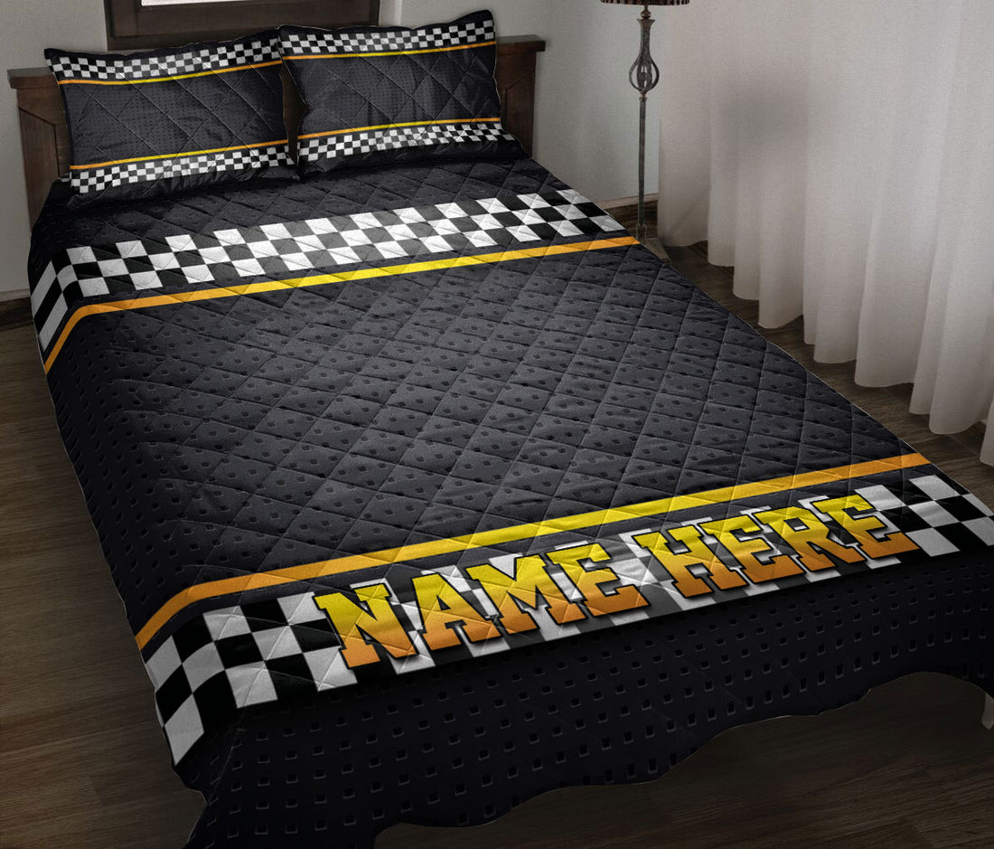 Black racing quilt blanket on a bed with checkered flag bands and yellow accent stripes