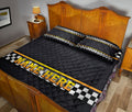 Racing quilt blanket styled in a bedroom with black checkered flag bands and yellow trim