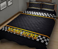 Black and yellow racing quilt blanket displayed on a bed with bold checkered flag artwork