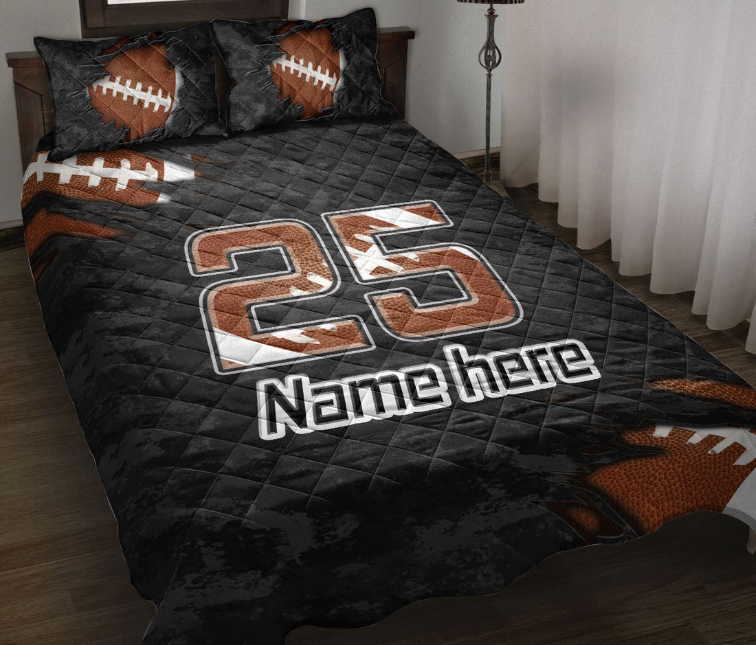 Black football quilt blanket displayed on a bed with orange footballs and bold jersey-style artwork
