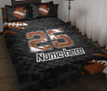 Black football quilt blanket displayed on a bed with orange footballs and bold jersey-style artwork