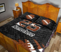 American football quilt blanket styled across a bedroom with bold orange, white, and black sports graphics