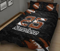 Black and orange football quilt blanket spread across a bed with large jersey-style sports artwork