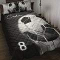 Black and white soccer ball quilt blanket styled on a bedroom bed with matching printed pillows