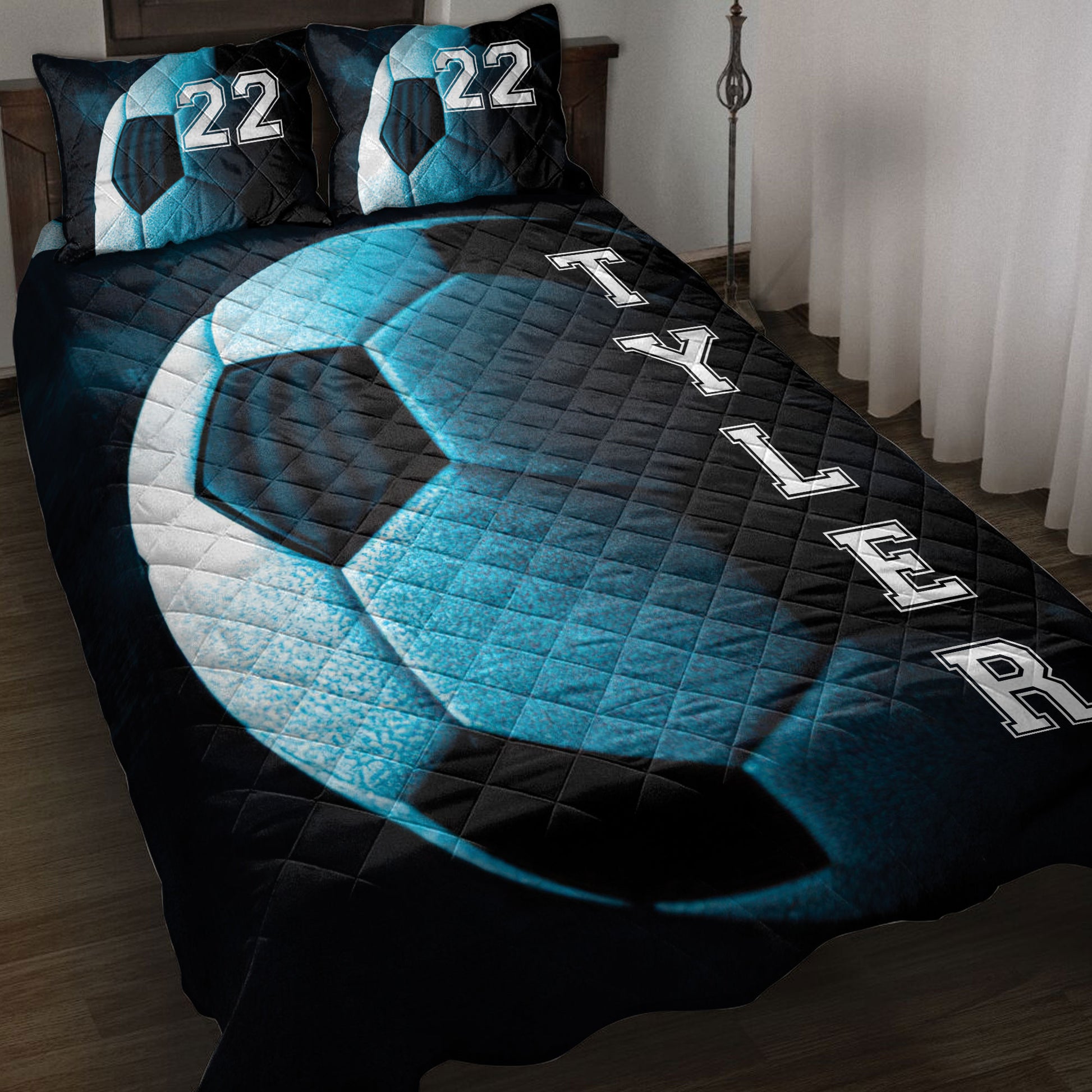 Black and blue soccer quilt blanket styled on a bed with bold varsity-inspired lettering