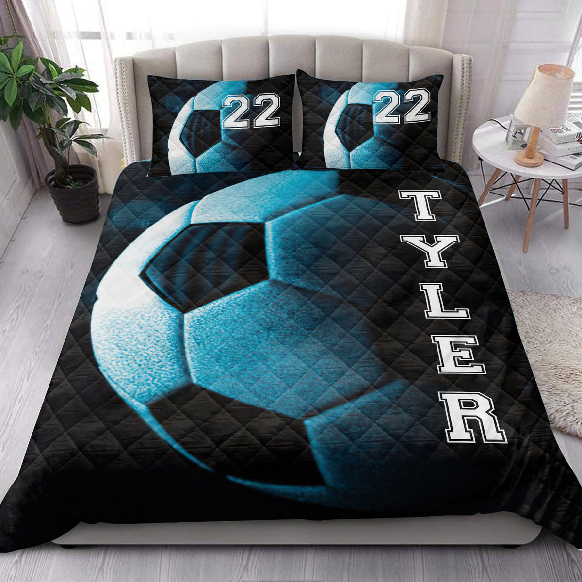 Black and blue soccer quilt blanket arranged in a bright bedroom with matching design accents