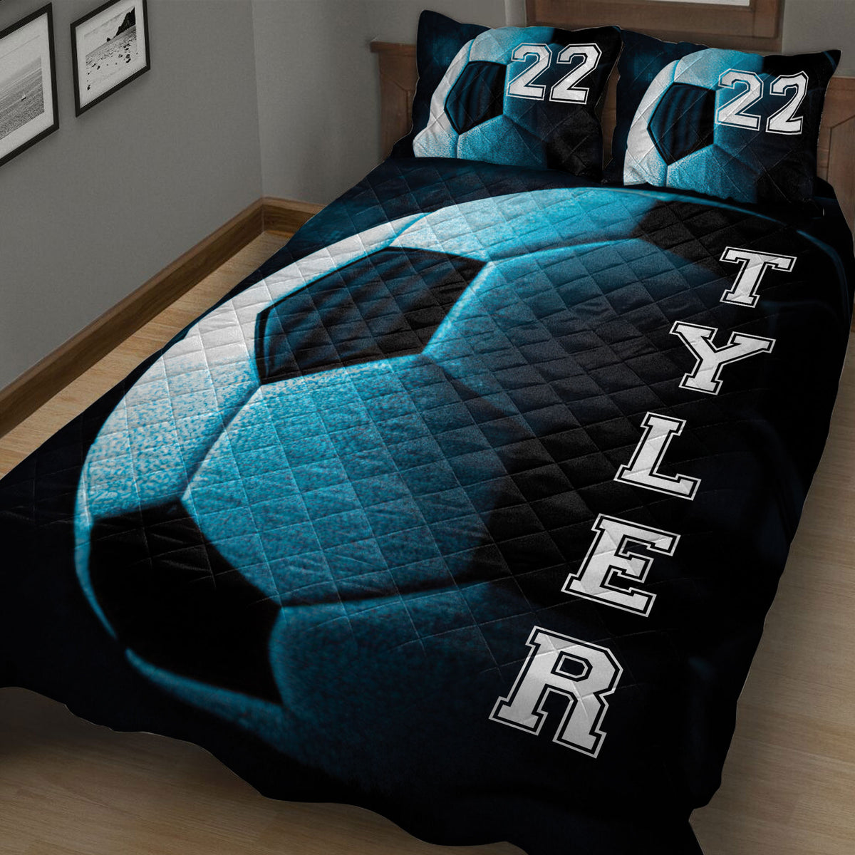 Close bedroom view of a dark soccer quilt blanket with blue ball artwork and varsity-style lettering