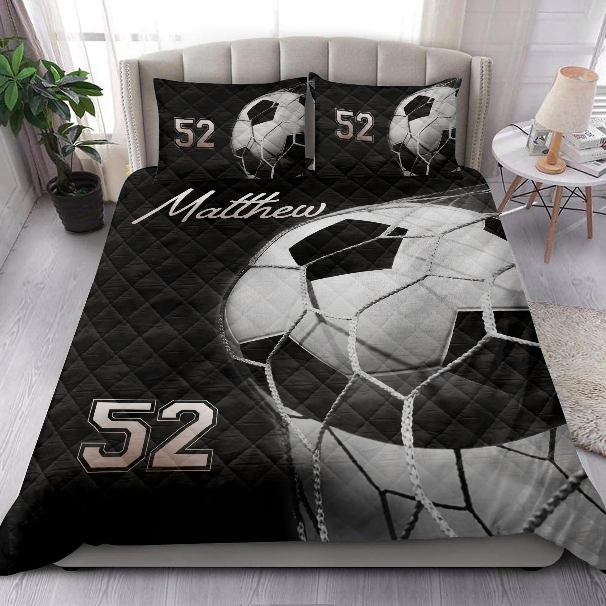 Black soccer ball quilt blanket styled across a modern bedroom with matching pillow designs
